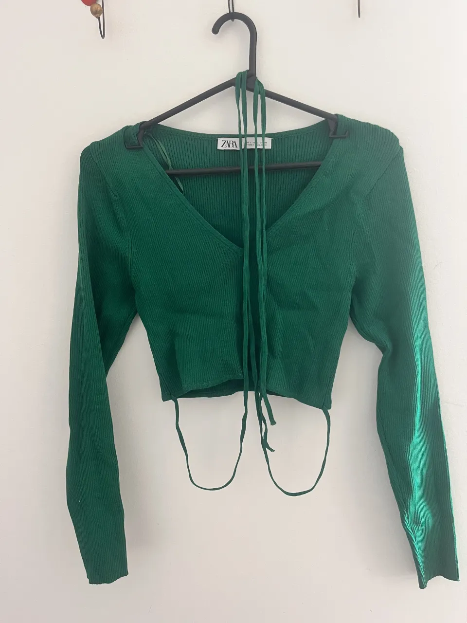 Remera manga larga de tejido acanalado color verde. Posee escote en V y tiras para atar en la espalda.