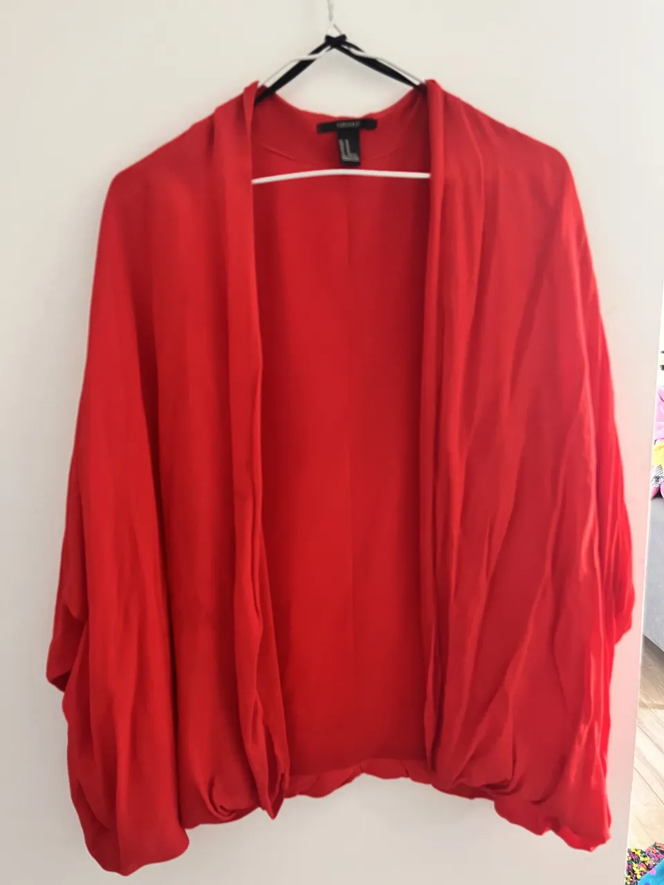 Cardigan rojo de manga ancha, sin botones ni cierres.