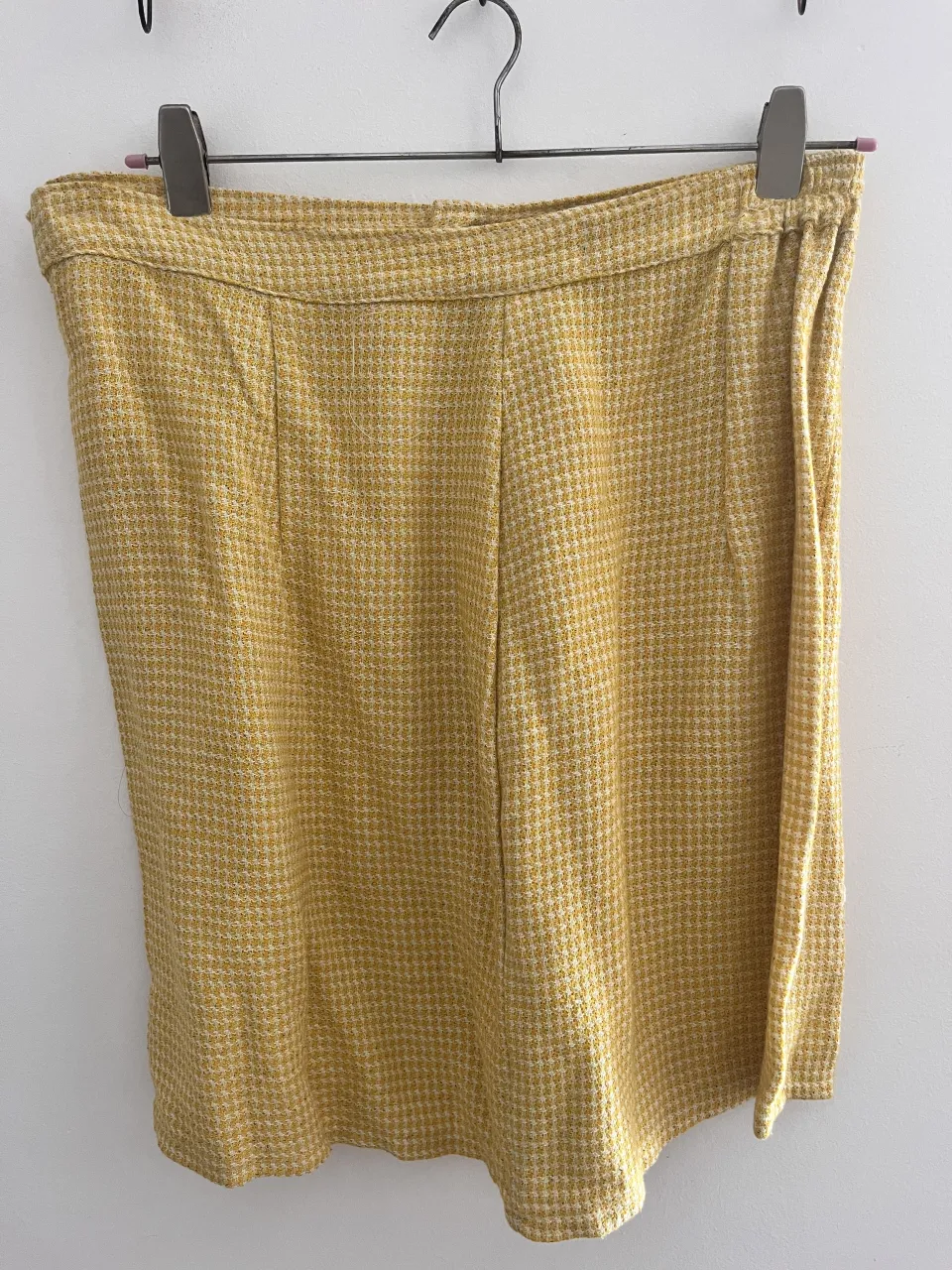 conjunto de pollera y chaqueta amarillos con estampado de cuadros pequeños en blanco y amarillo. Tienen dos botones plateados en la parte delantera.