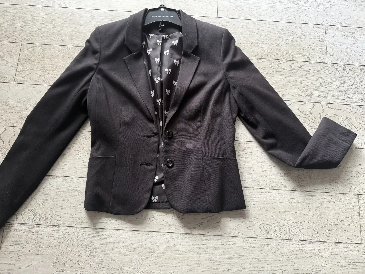 Blazer negro de mujer, con forro interior estampado con moños. Ideal para un look formal o de trabajo.