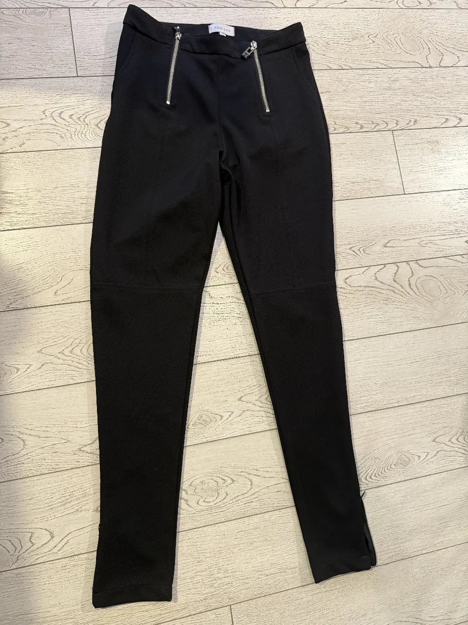 Pantalón sastrero negro con detalles de cierre en la cintura y en los tobillos. Diseño elegante y versátil, ideal para crear looks formales o casuales.