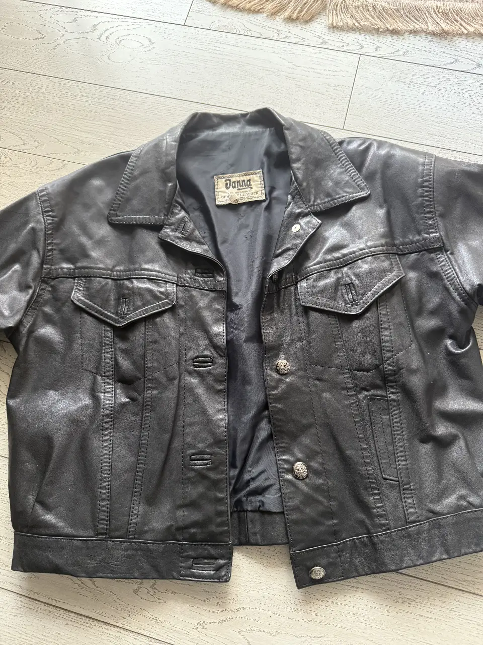 Campera de cuero negra Donna, estilo biker, con detalles de costura y botones plateados. Ideal para un look rocker o casual.
