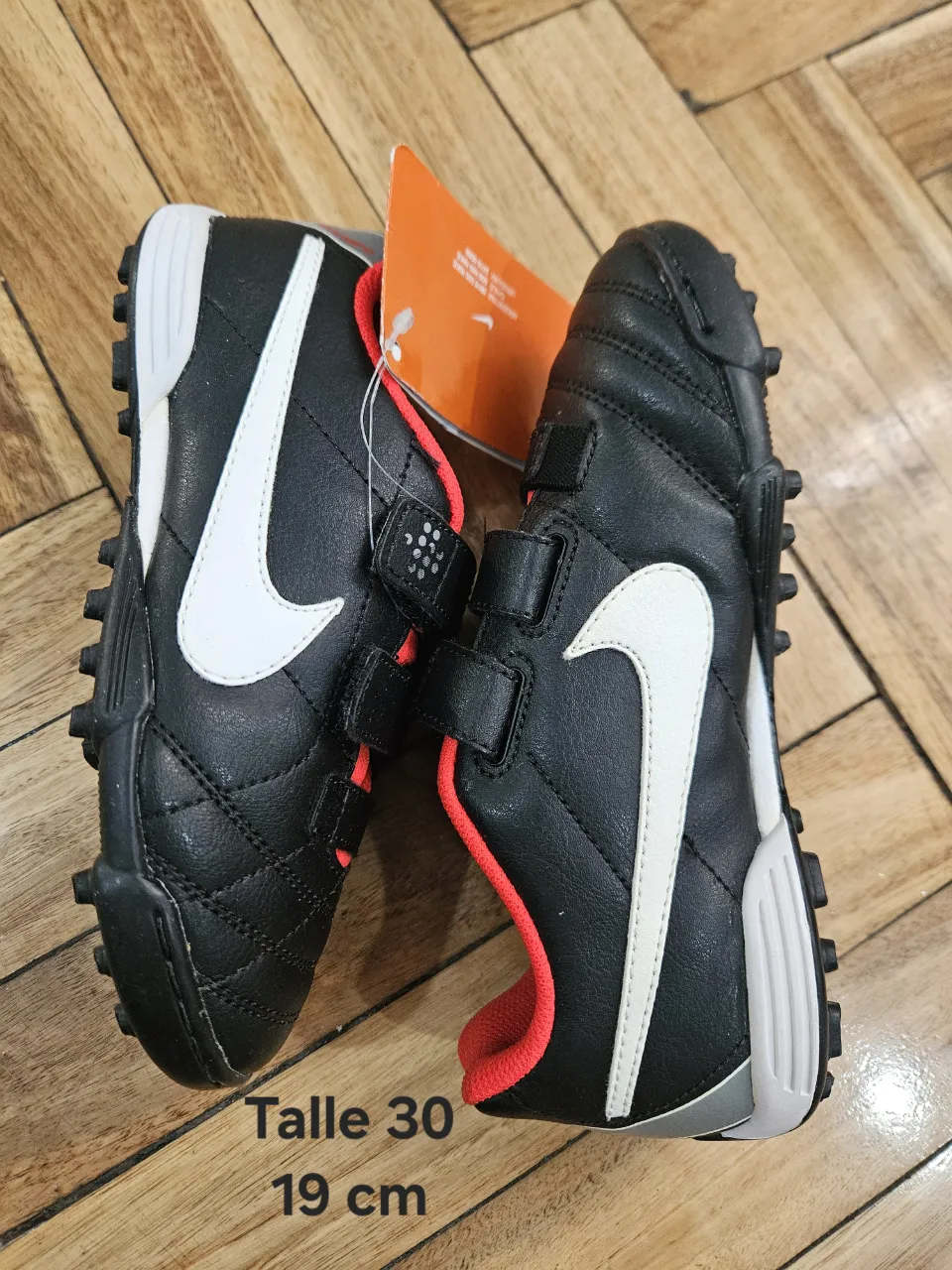 Zapatillas de fútbol para niños Nike, color negro con detalles en blanco y rojo. Talle 30, ideales para jugar en césped sintético.