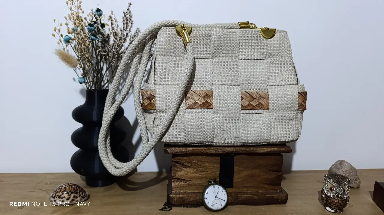 Cartera artesanal de diseño único, tejida con materiales naturales en tonos crudos y detalles marrones. Ideal para un look casual y bohemio.