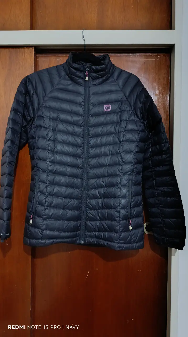 Campera de pluma negra para mujer, ideal para el invierno. Con cierre frontal, cuello alto y logo de la marca en el pecho. Talle M.