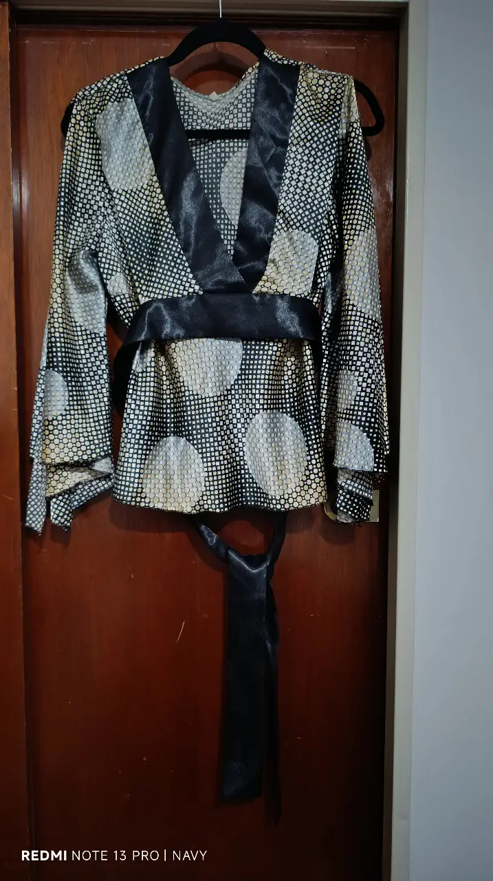 Blusa de mujer con estampado de lunares y detalles en negro. Diseño elegante con cinturón para ajustar la cintura. Ideal para eventos especiales o para darle un toque sofisticado a tu look diario.