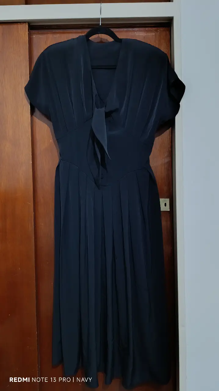 Vestido midi negro, con detalle de lazo en el cuello y corte en la cintura. Ideal para eventos formales o salidas nocturnas. Talle 42.