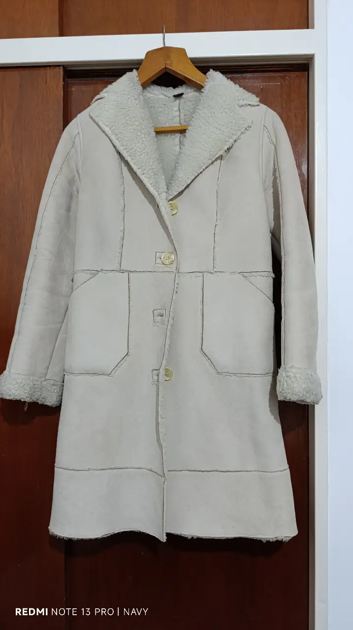 Tapado largo de mujer, color crudo, con cuello y puños de piel sintética. Posee tres botones y dos bolsillos delanteros. Ideal para el invierno.