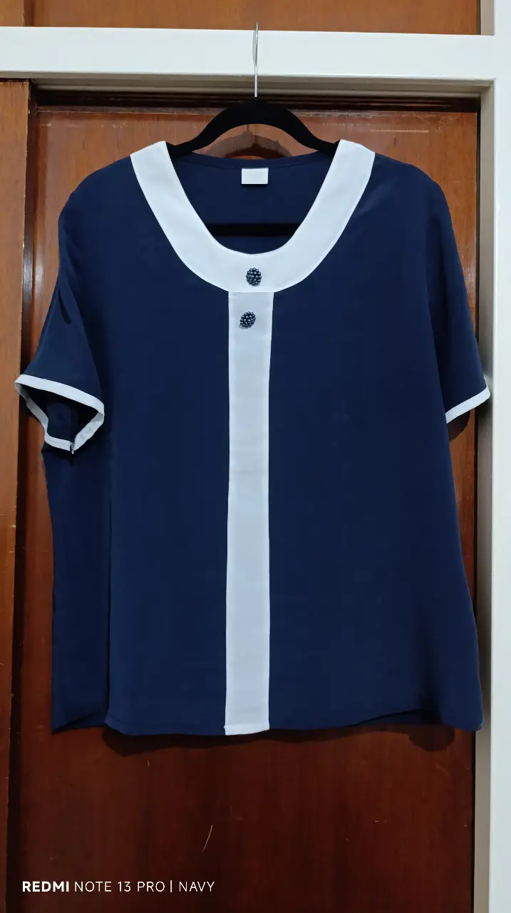 Blusa de mujer en color azul marino con detalles en blanco. Diseño elegante con cuello redondo y botones decorativos. Ideal para un look sofisticado y versátil.
