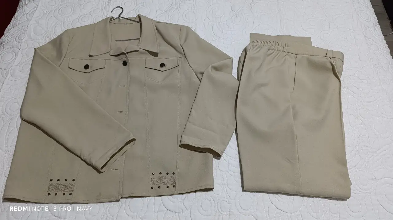 Conjunto sastrero de dos piezas en color crudo. Incluye blazer con solapas, bolsillos y detalles decorativos, y pantalón de corte recto. Ideal para un look elegante y versátil.