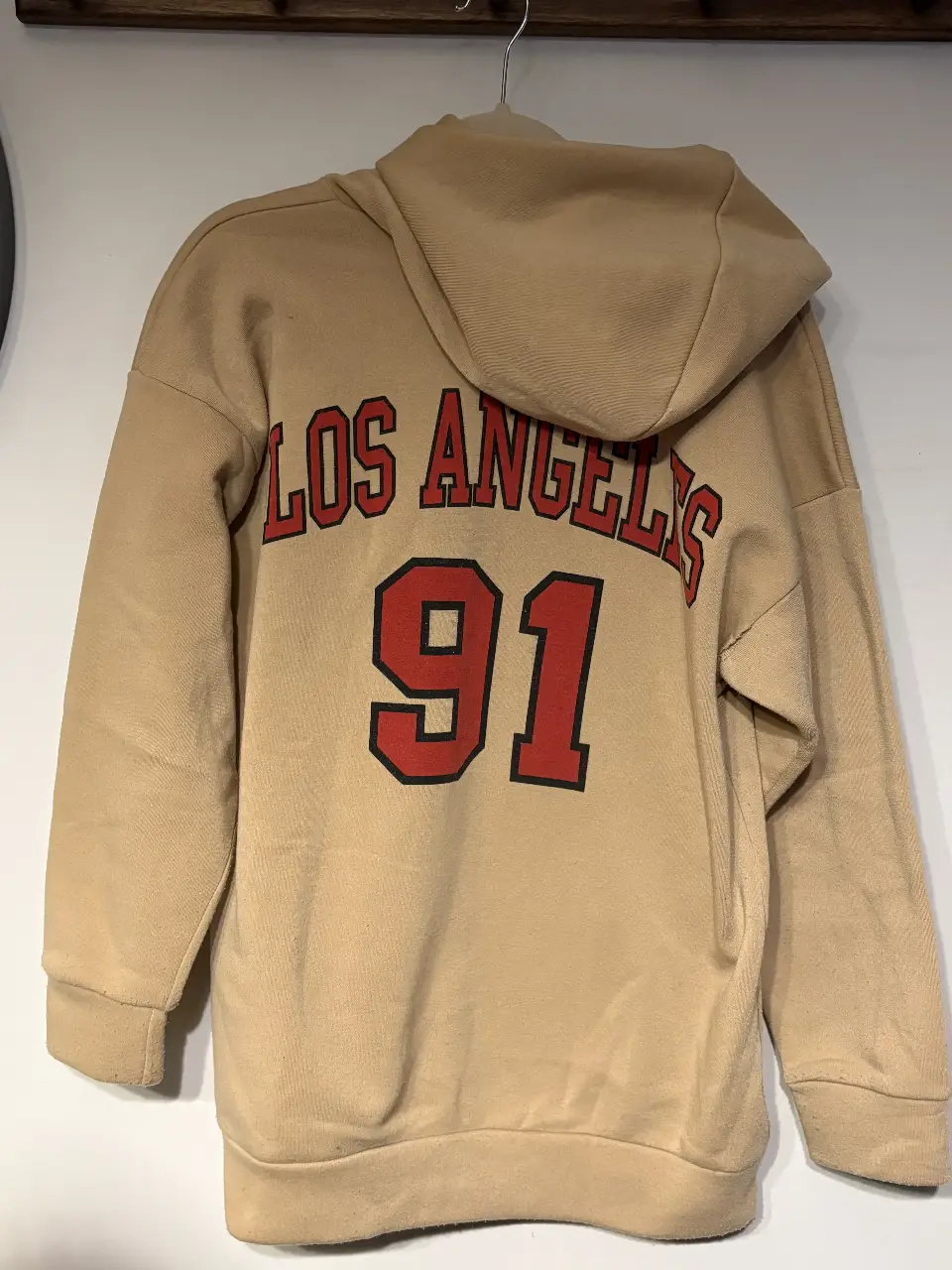 Buzo canguro de color crudo con estampado "LOS ANGELES 91" en la espalda. Ideal para un look casual y urbano.