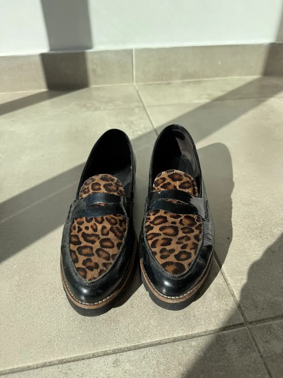 Elegantes mocasines de cuero charolado negro con detalle de estampado animal print en la parte superior. Perfectos para un look sofisticado y moderno. importados Holanda 