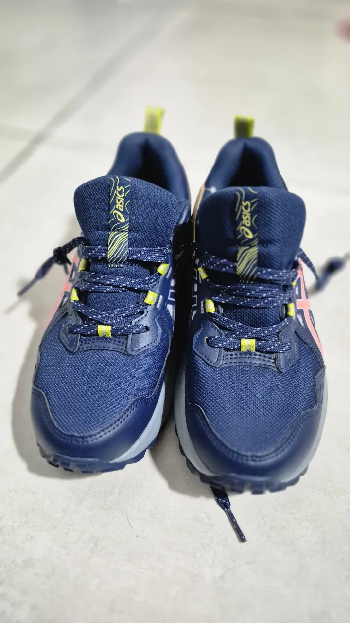 Zapatillas deportivas de color azul marino con detalles en rosa y amarillo. Tienen cordones y el logo de la marca en los laterales.