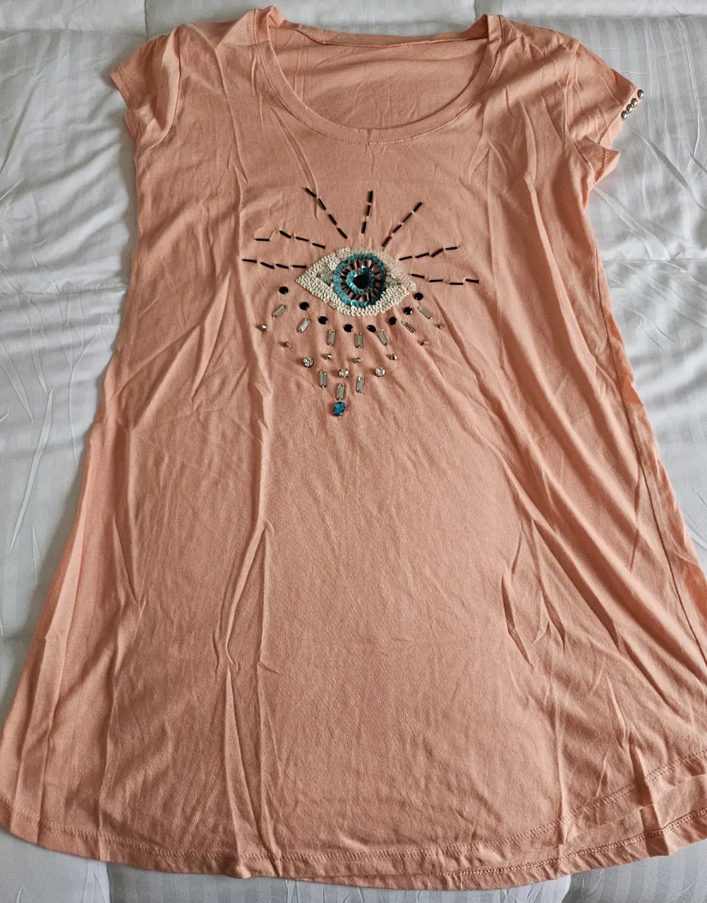 Vestido mini de color rosa con un diseño de ojo bordado en el frente. Ideal para un look casual y fresco.