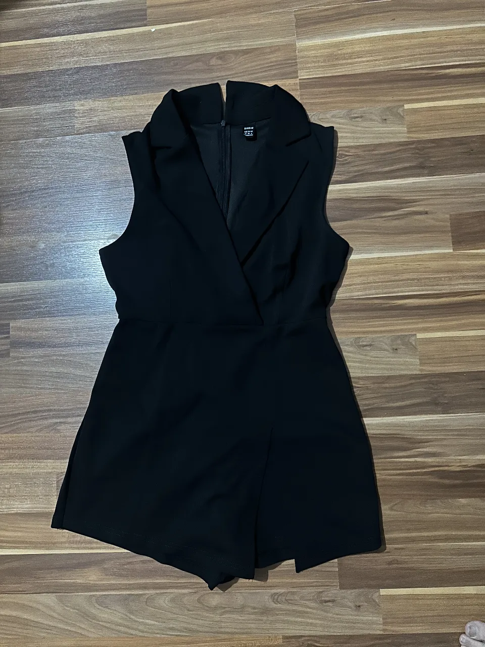 Mono corto de mujer, negro, con cuello solapa y cierre frontal. Ideal para un look elegante y moderno. Tiene short debajo y simula ser pollera. Tiene corte de blazer arriba. lo vendo porque me quedó un poco grande 