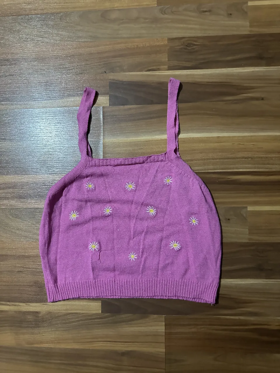 Top tejido de color rosa con bordado de flores amarillas. Ideal para un look casual y fresco.
