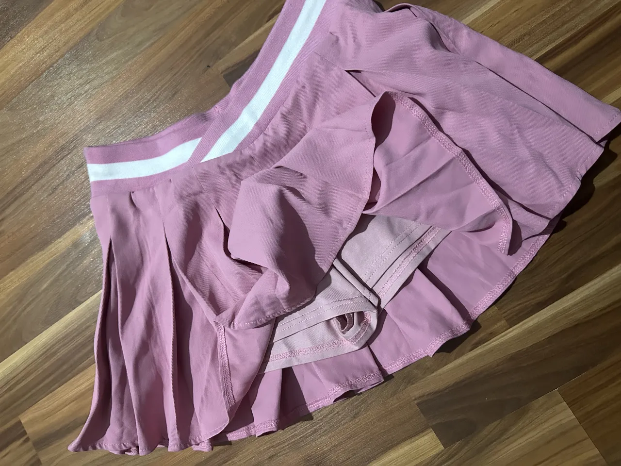 Minifalda plisada rosa con cintura blanca. Short debajo. Ideal para un look casual o deportivo. 