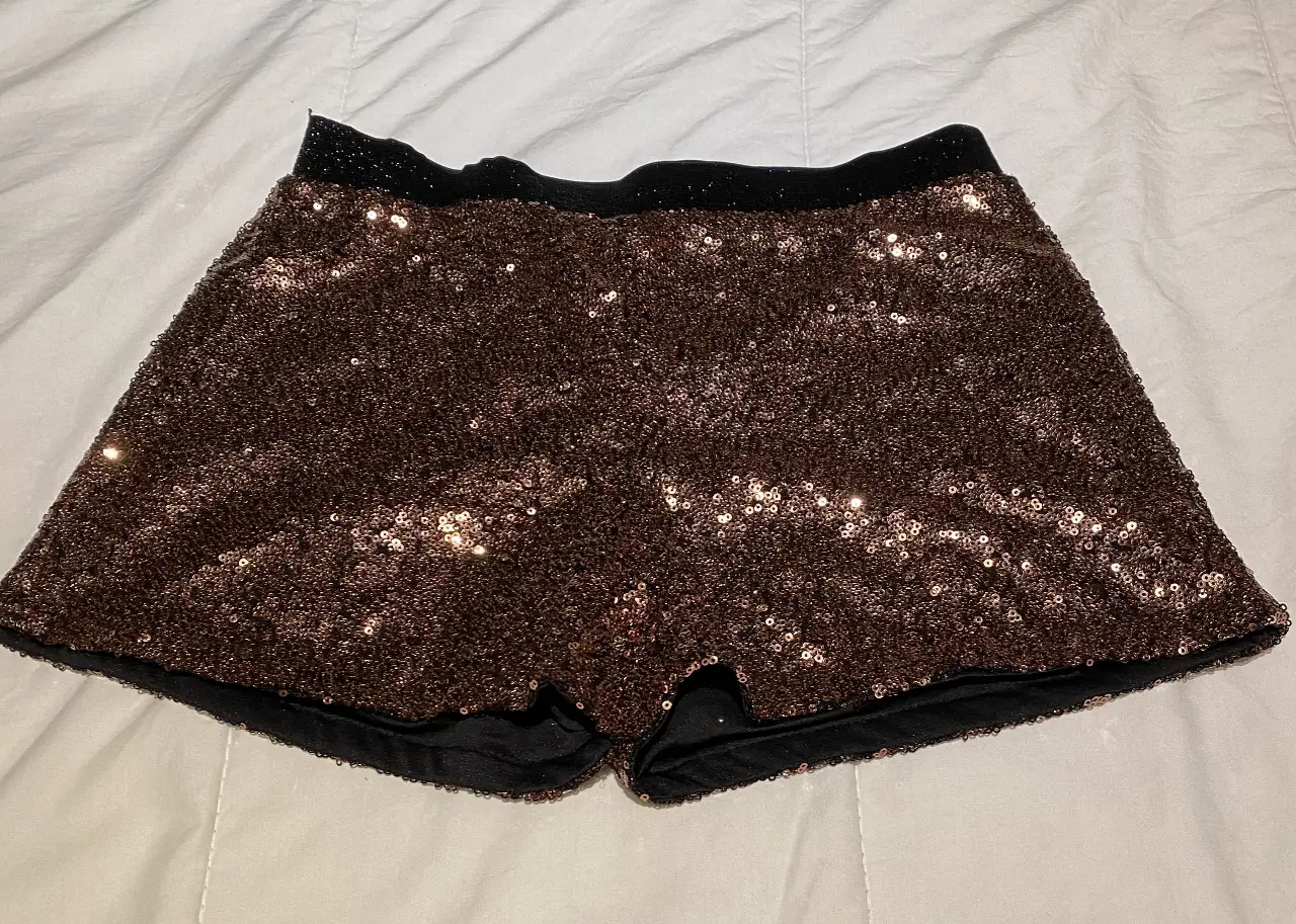 Shorts de mujer tiro alto con lentejuelas color marrón. Ideal para fiestas y eventos especiales. Detalles en negro en la cintura y borde inferior.