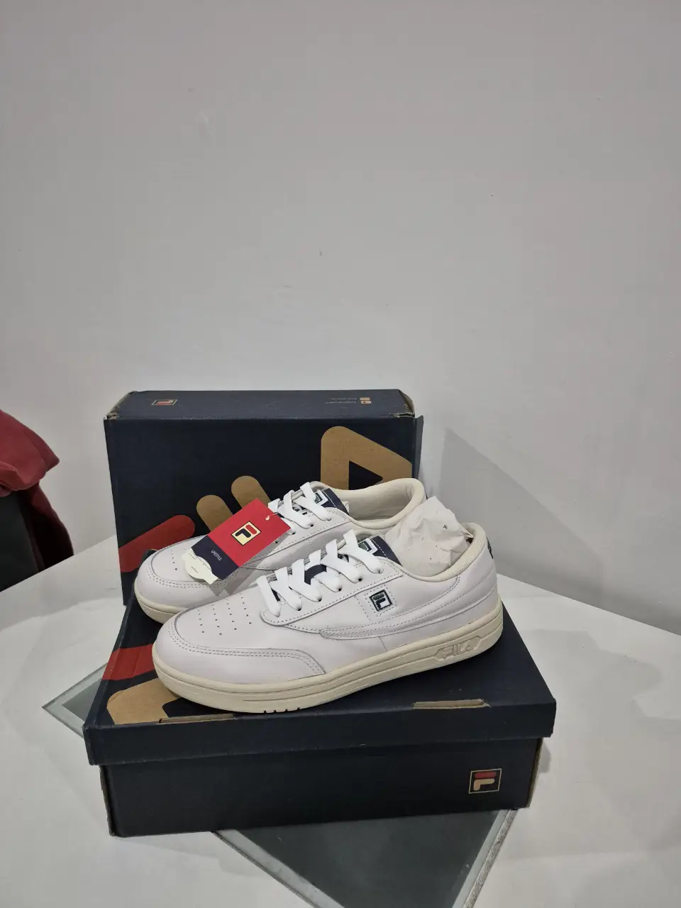 Zapatillas Fila blancas, estilo clásico, con detalles en verde y azul. Ideales para un look casual y cómodo.