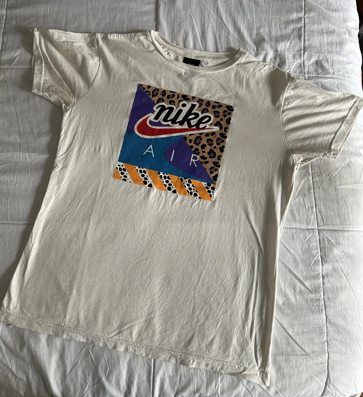 Remera Nike Air blanca con estampado retro en el frente. Diseño con logo y detalles de animal print. Talle M. detalles en la última foto