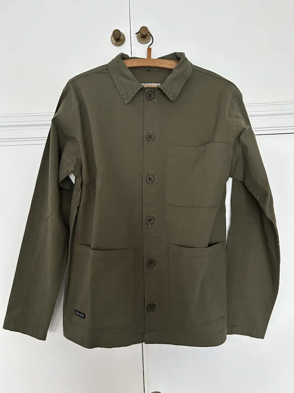 Camisa de hombre de estilo utilitario en color verde oscuro. Confeccionada en gabardina resistente, presenta un diseño clásico con botones y bolsillos frontales. Ideal para un look casual y funcional. Tela gruesa