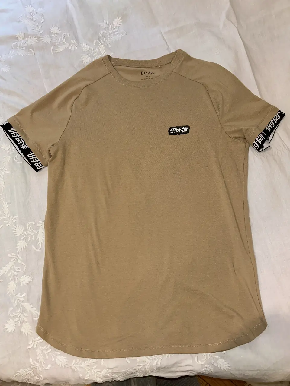 Remera manga corta de hombre, color khaki, con detalles en las mangas y un pequeño logo en el pecho. Ideal para un look oversize casual y moderno.