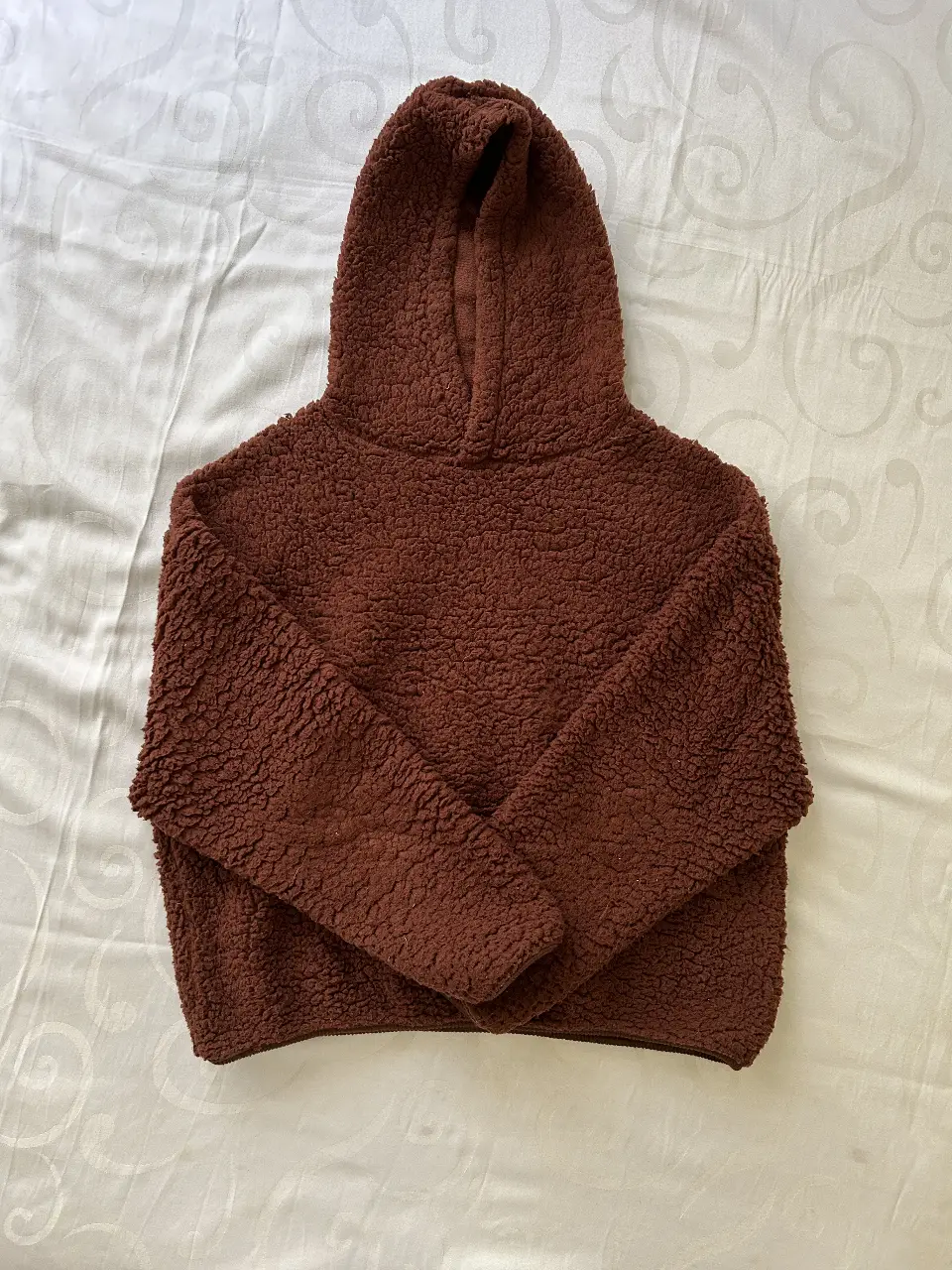 Buzo peluche canguro de tela tipo sherpa, color marrón. Ideal para un look cómodo y abrigado.