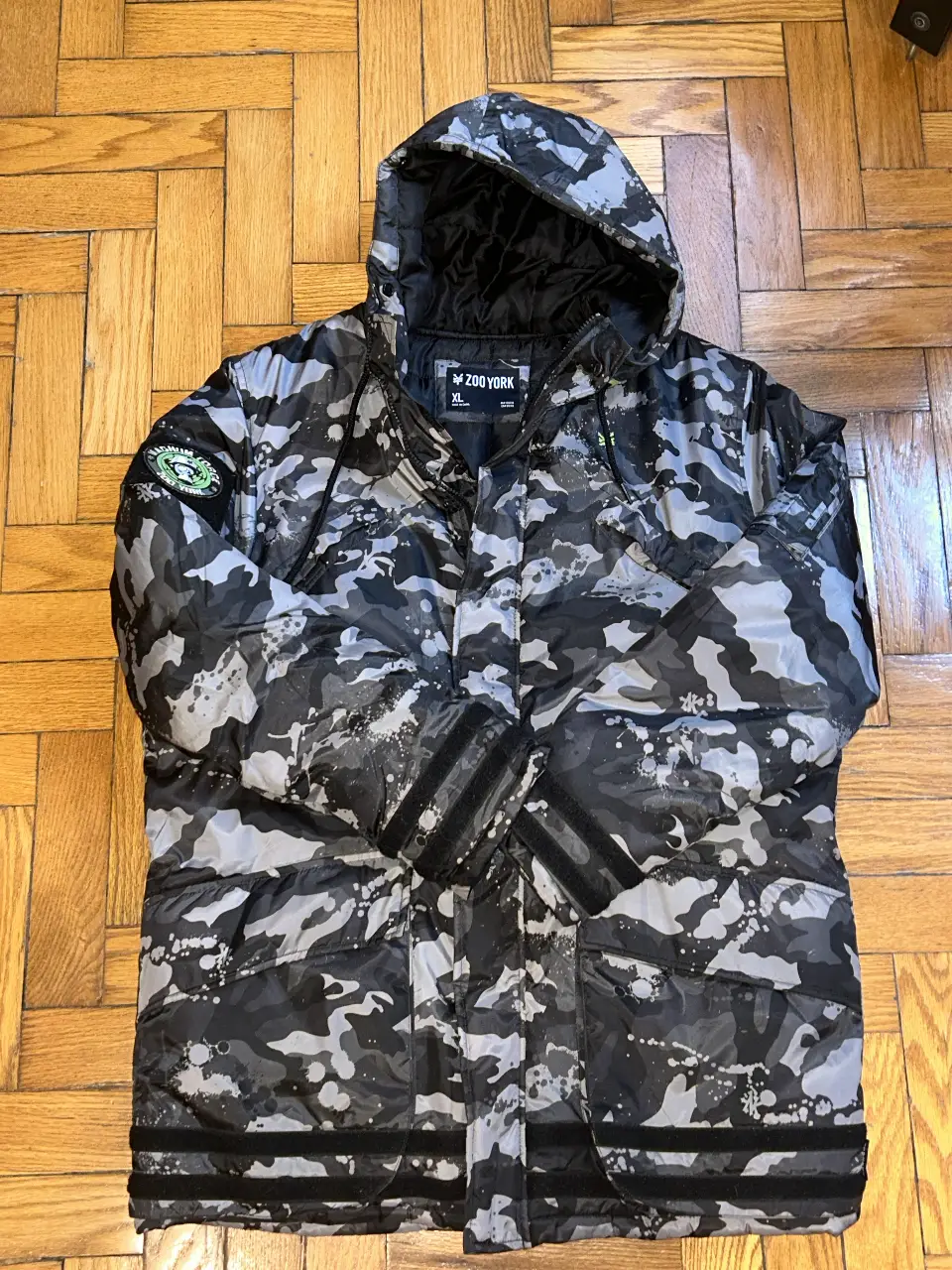 Campera de abrigo Zoo York con estampado camuflado en tonos grises y negros. Posee capucha y cierre frontal. Ideal para el invierno.