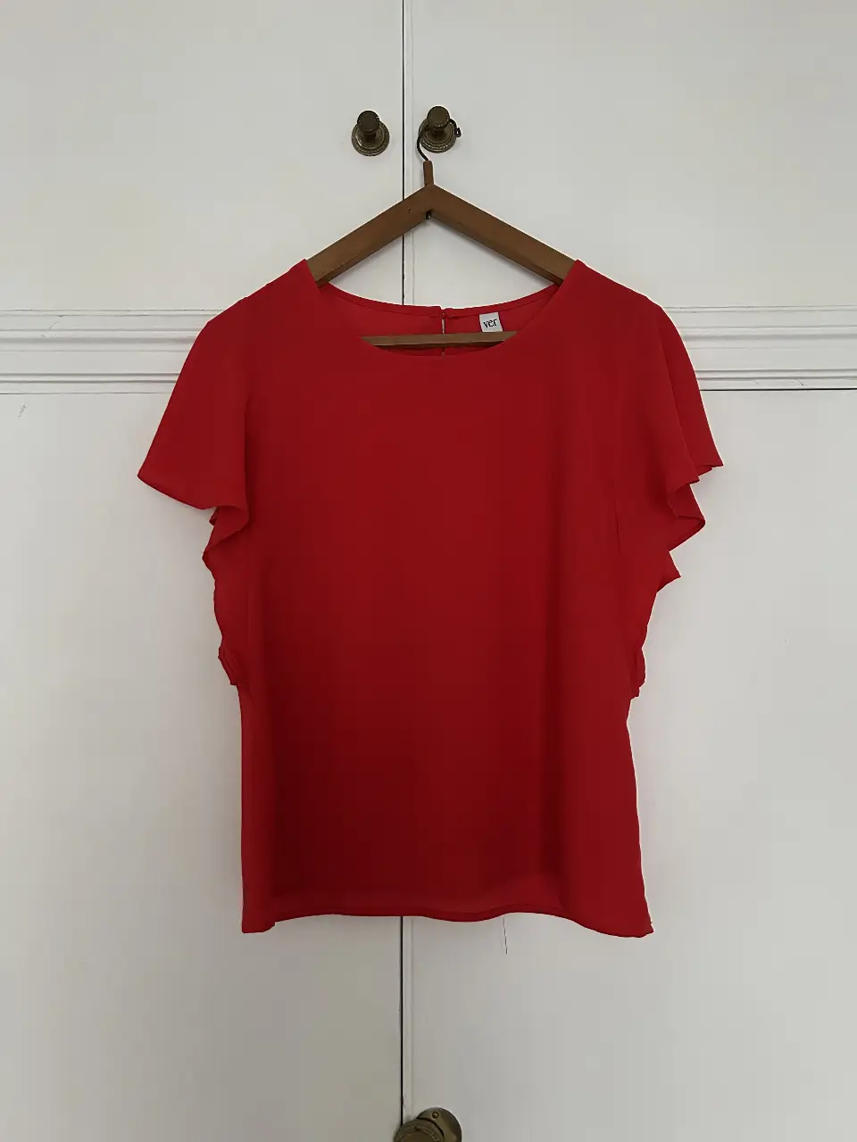 Blusa roja con mangas cortas con volados, ideal para un look fresco y femenino. Confeccionada en tela liviana y cómoda, perfecta para combinar con diferentes outfits.