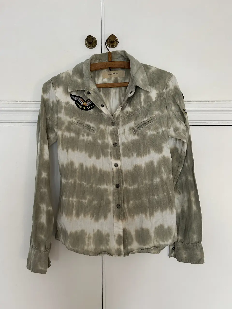 Camisa con estampado tie dye en tonos grises y blancos. Detalles de parches en mangas y pecho. Marca Rapsodia. Talle S. Medidas: 58cm largo total, 50cm de axila a axila, 42cm de hombro a hombro, 64cm largo de manga desde hombro