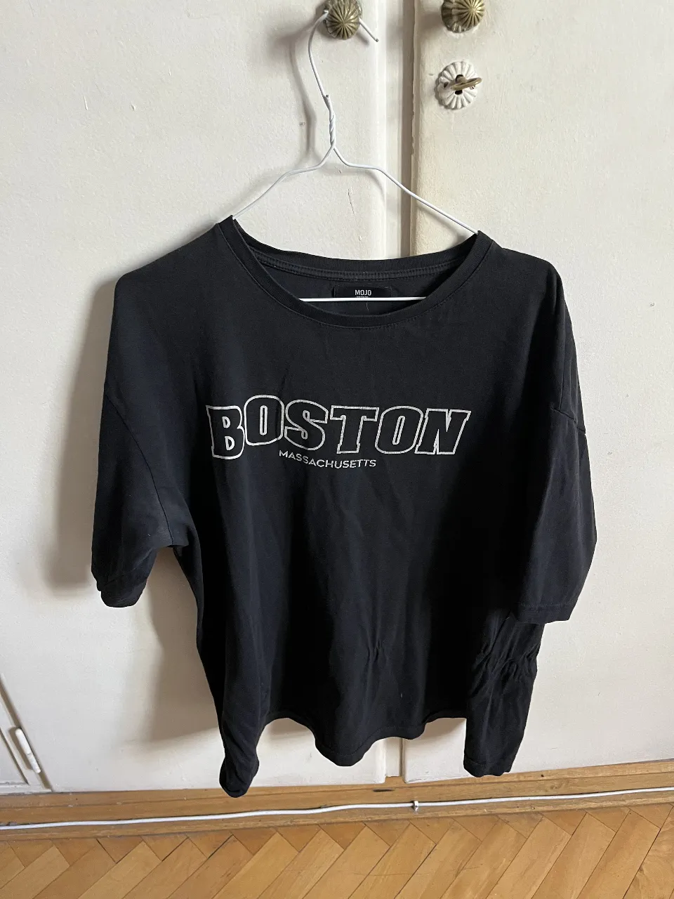 Remera negra de hombre con estampado "BOSTON MASSACHUSETTS" en blanco. Cuello redondo y mangas cortas. Ideal para un look casual y urbano.