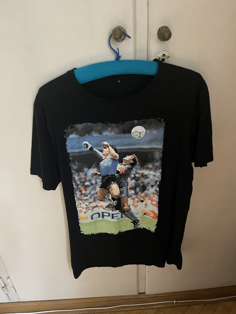 Remera negra de hombre con estampado de Diego Maradona en la icónica jugada del gol a Inglaterra en el Mundial 86. Talle M.