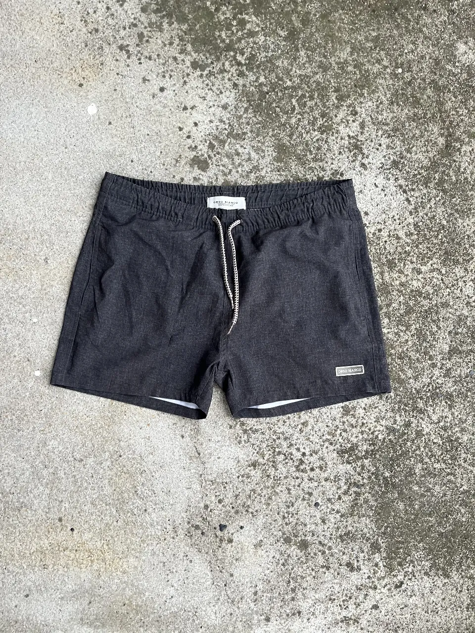 Short de baño negro de hombre, con cordón blanco y etiqueta de la marca. Ideal para la playa o pileta.