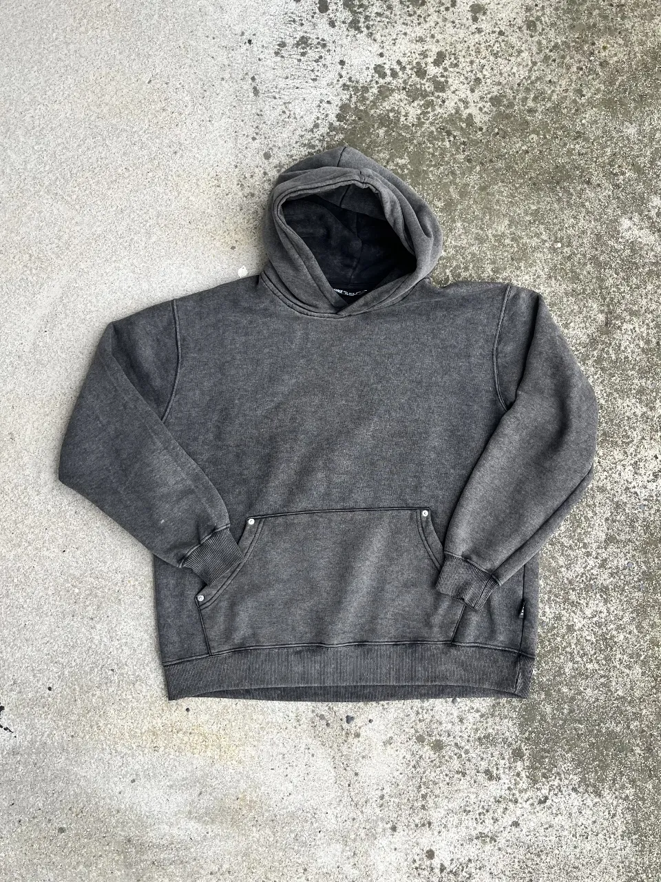 Buzo canguro de hombre, color gris gastado, con capucha y bolsillo frontal. Ideal para un look casual y cómodo.