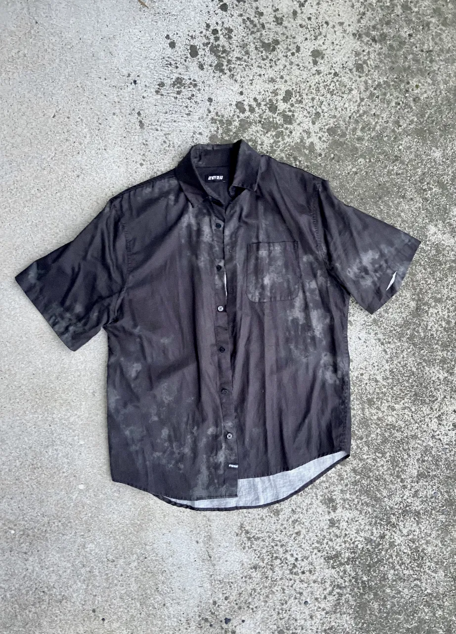 Camisa de manga corta negra con diseño tie-dye. Ideal para un look casual y moderno.