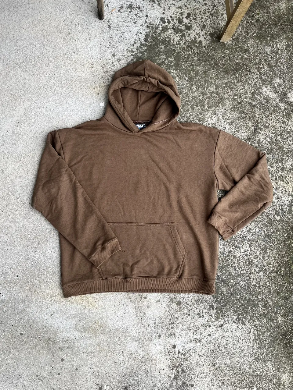 Buzo canguro de hombre, color marrón, con capucha y bolsillo frontal. Ideal para un look casual y cómodo.