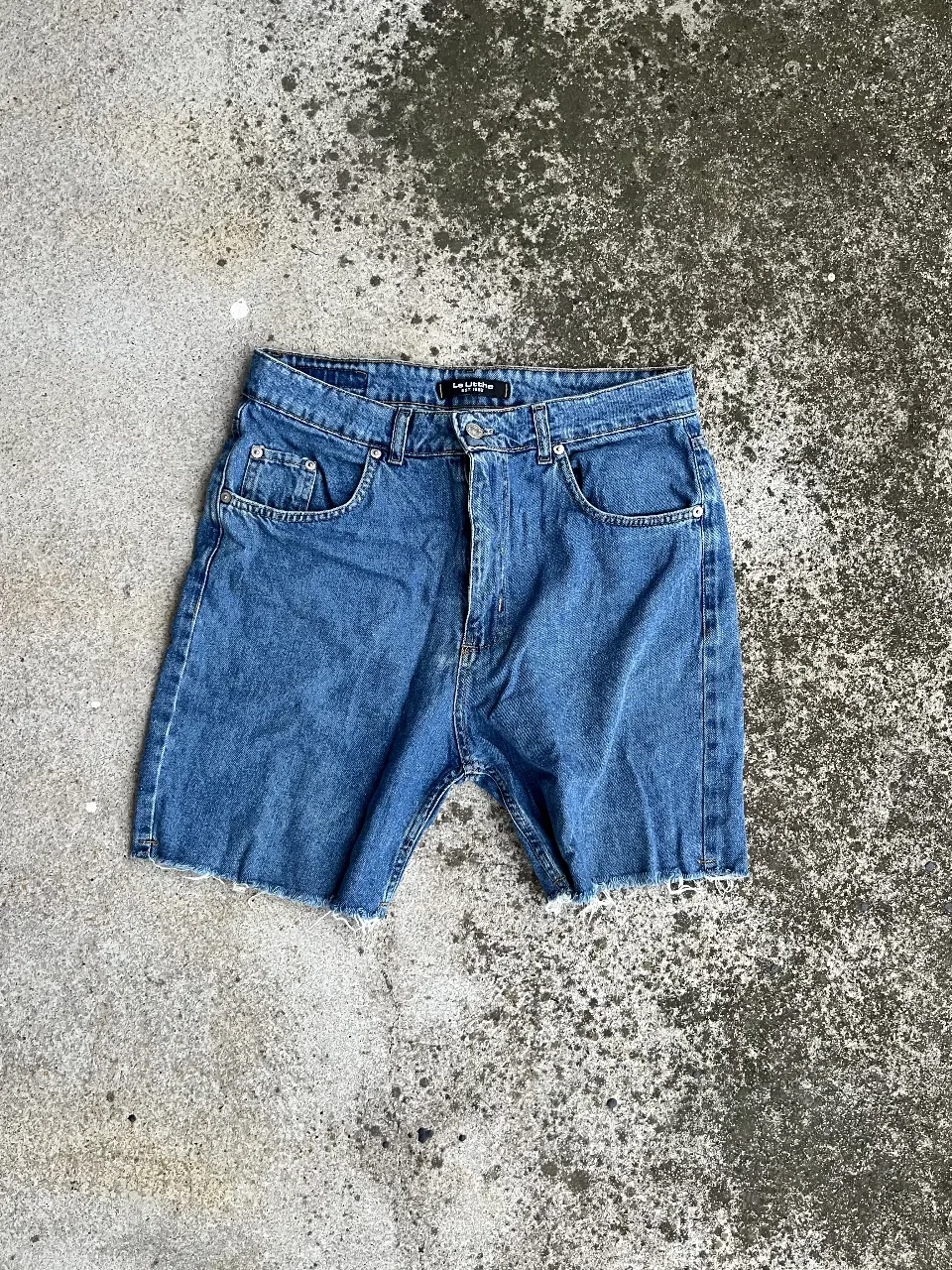Short de jean azul, con corte desflecado en el borde inferior. Tiro medio, ideal para un look casual y fresco.