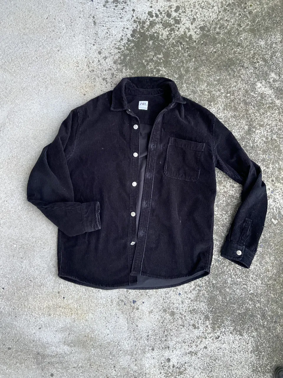 Camisa de corderoy negra de hombre, con bolsillo en el pecho y botones. Ideal para un look casual y canchero.