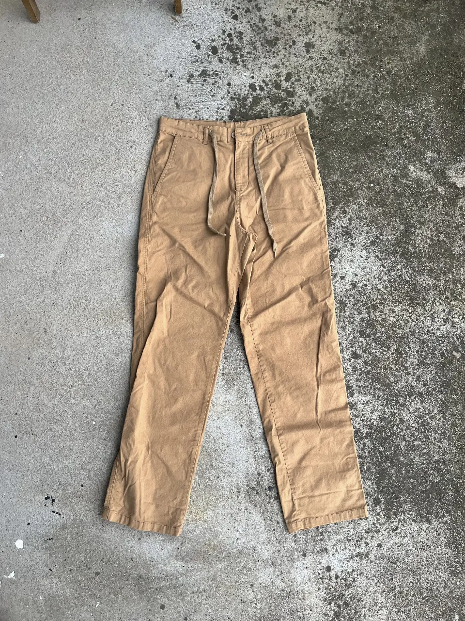 Pantalón chino color marrón claro, con cordón en la cintura y bolsillos delanteros y traseros. Ideal para un look casual y cómodo.