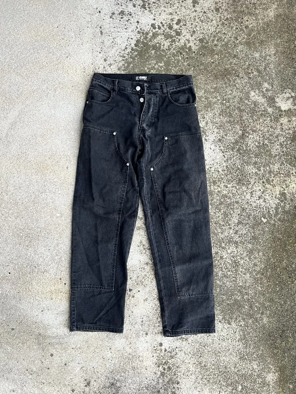 Jeans negro de hombre, corte recto, con detalles de costuras en las rodillas y bolsillos delanteros. Ideal para un look casual y moderno.