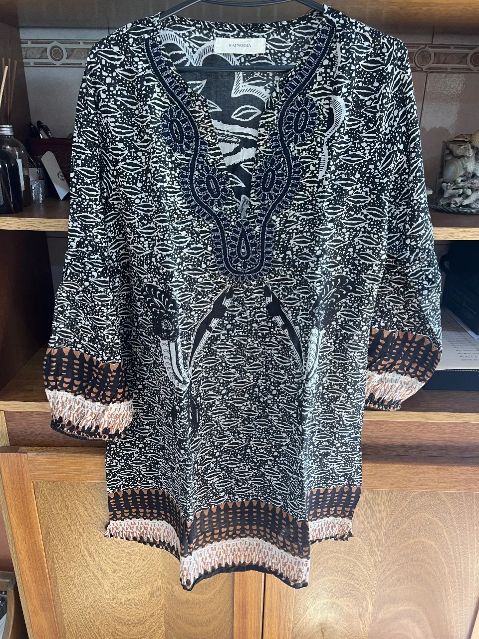 Blusa estampada con diseño en blanco y negro, con detalles bordados en el cuello y puños. Estilo boho, ideal para un look casual y con personalidad.