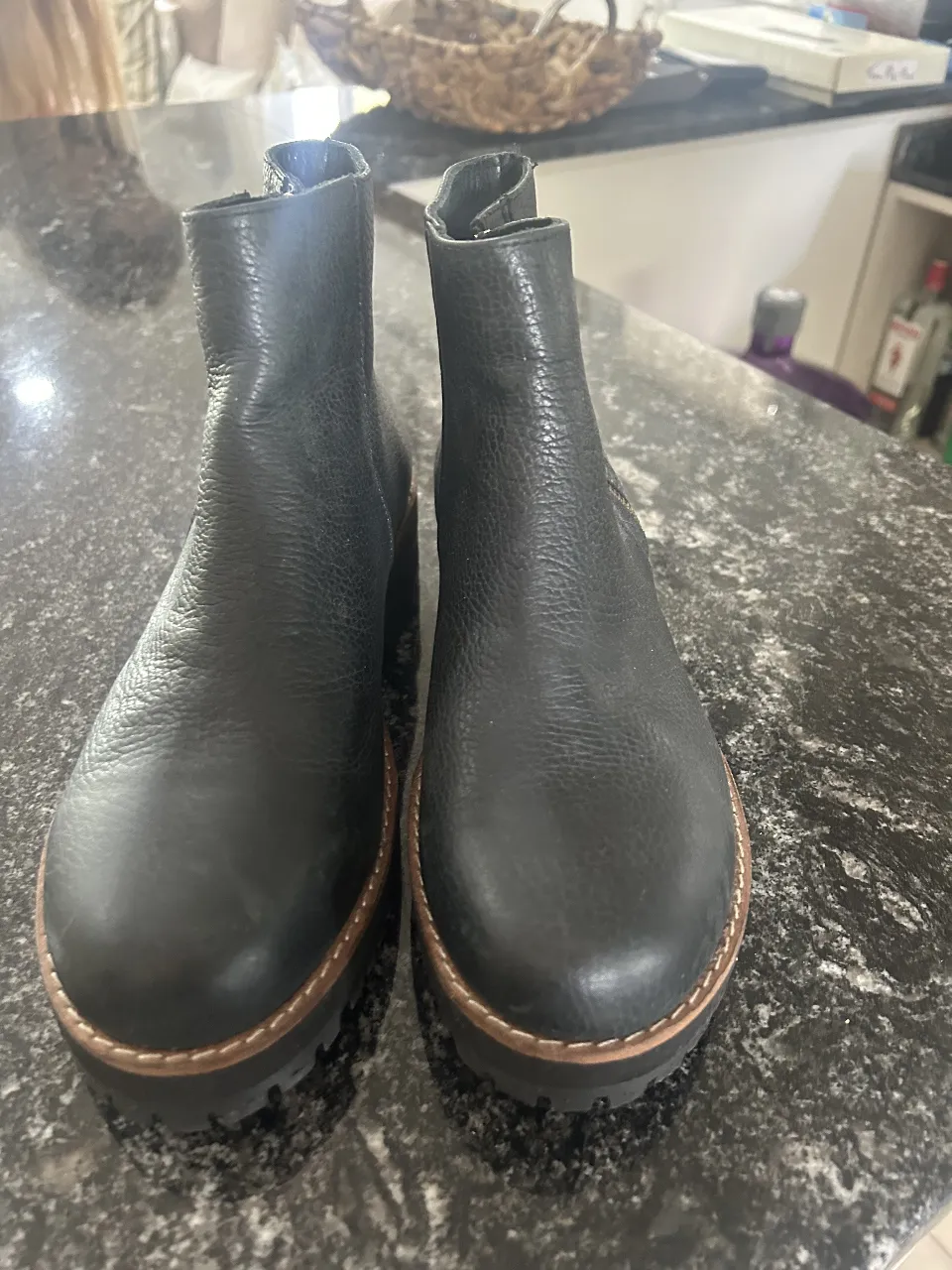 Botines de cuero negro con suela de goma. Diseño moderno y versátil, ideales para combinar con diferentes outfits. Cierre con cremallera lateral y detalles de costura en la suela.