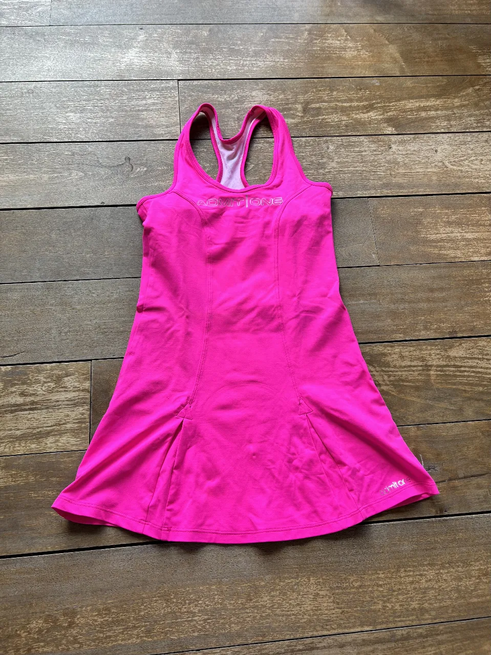 Vestido deportivo rosa fucsia para mujer, con espalda cruzada y detalles de costura. Ideal para actividades deportivas.