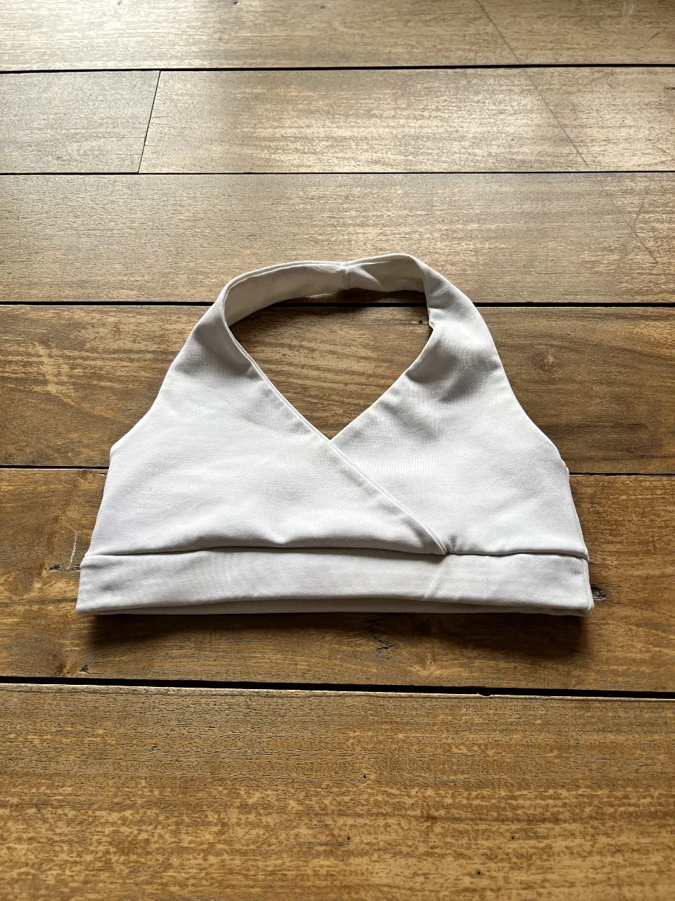 Top deportivo blanco con diseño halter y detalle de la marca "ADMIT ONE". Ideal para actividades de bajo impacto. Confeccionado en tela suave y transpirable.