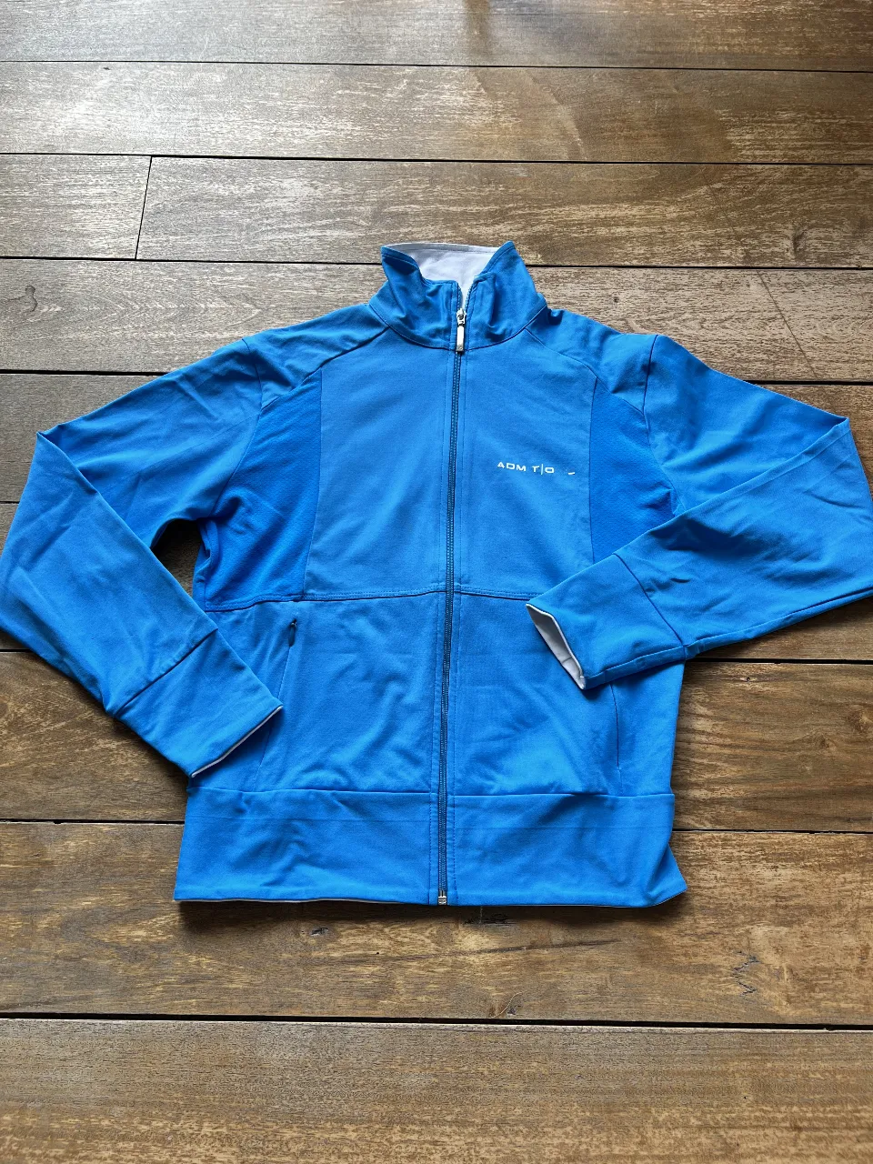 Buzo deportivo azul con cierre y detalles en blanco. Ideal para actividades al aire libre o para un look casual y cómodo. Marca ADMIT ONE