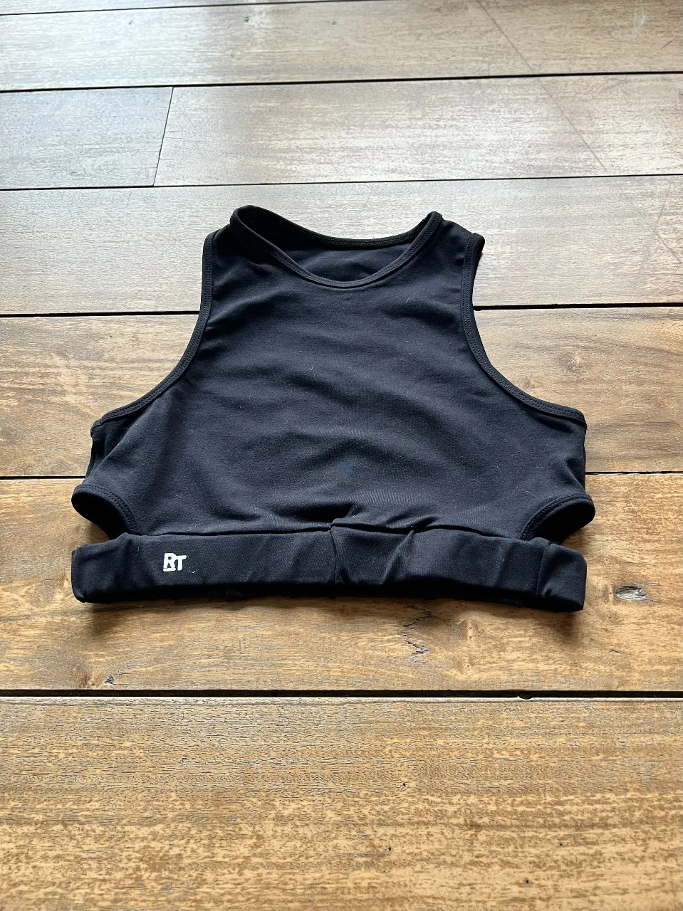 Top deportivo negro con diseño cut-out. Ideal para entrenamientos de alto impacto. Confeccionado en tela suave y elástica para mayor comodidad y libertad de movimiento.