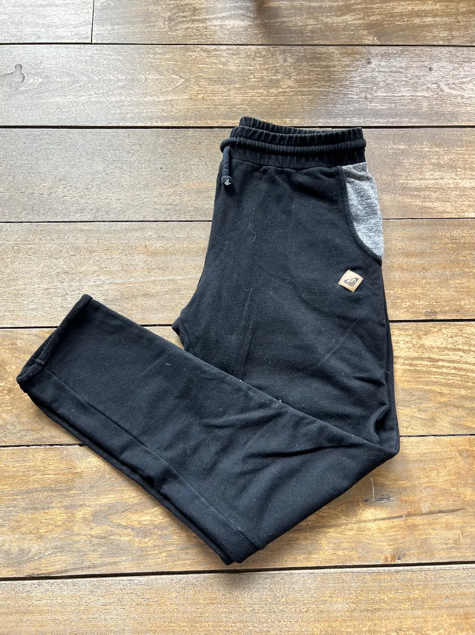 Pantalón de jogging negro de mujer, con detalles en gris en los bolsillos y cintura elastizada con cordón. Ideal para un look casual y cómodo.