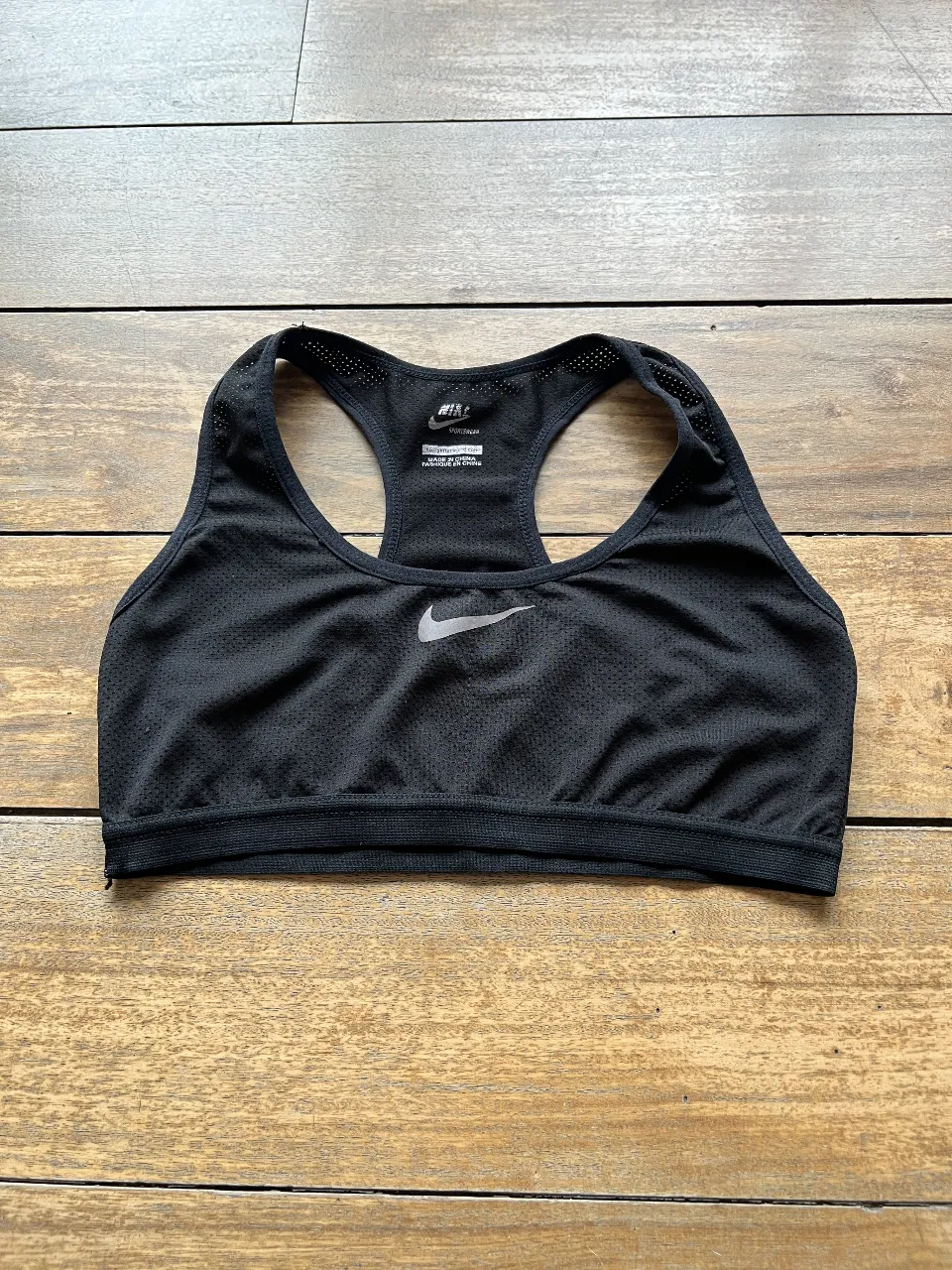 Top deportivo Nike negro, ideal para entrenamientos. Confeccionado en tela respirable y diseño con logo de la marca.
