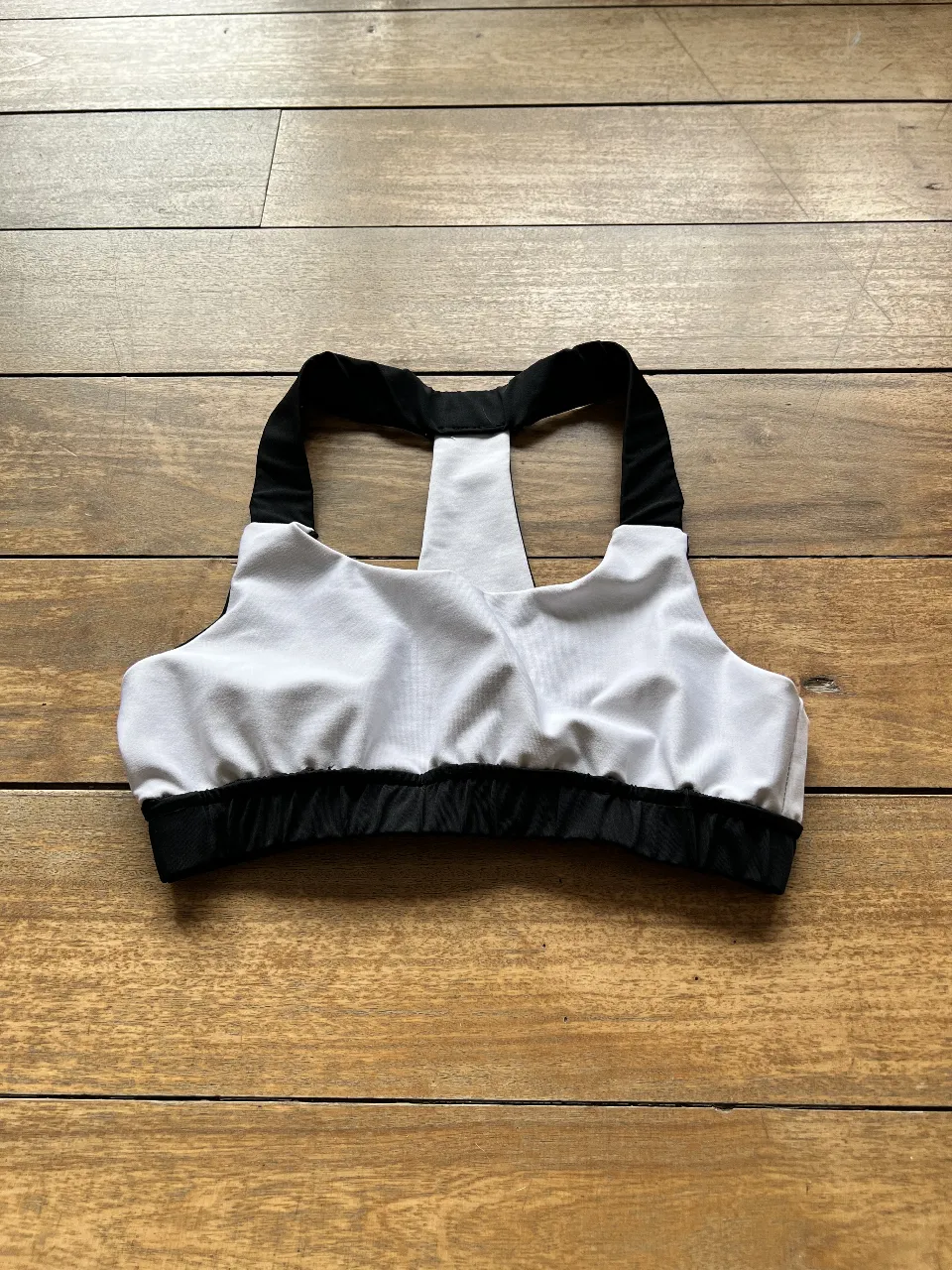Top deportivo para mujer, con diseño bicolor en blanco y negro. Ideal para actividades de bajo impacto. Confeccionado con materiales ligeros y transpirables. se puede utilizar de ambos lados. 