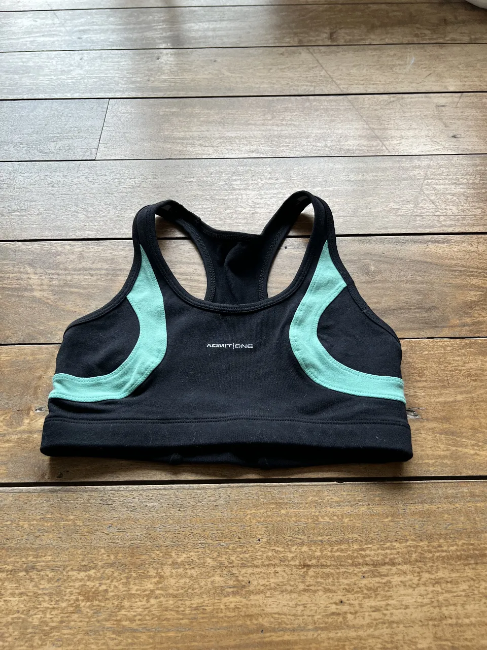 Top deportivo negro con detalles en verde. Ideal para entrenamientos de alto impacto. Marca Admit One.
